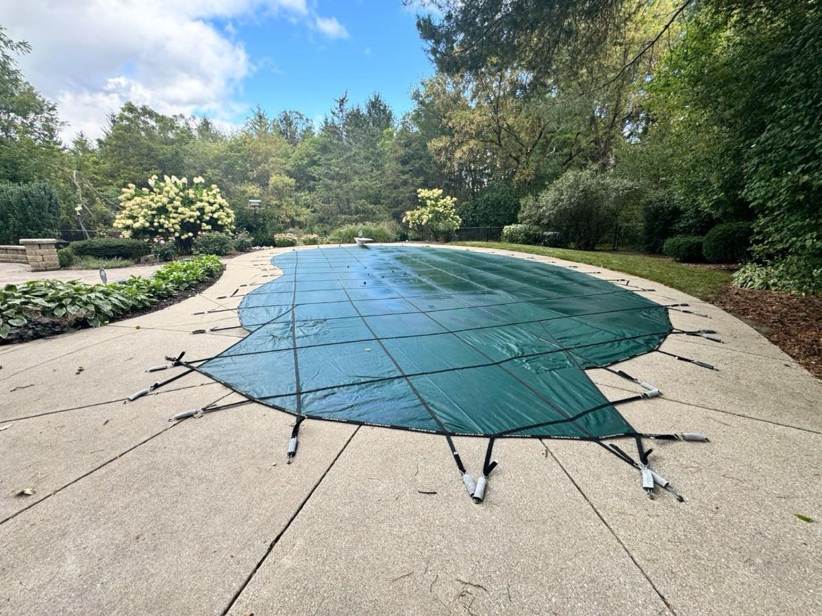 In-ground pool winterized with a green safety cover by Heartland Pool and Spa in Hartland WI